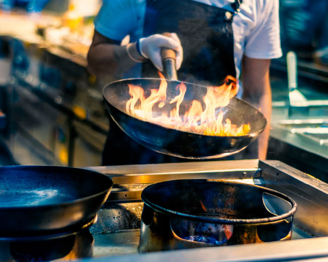 Chef Using a Wok in a Kitchen With Flames in the Pan